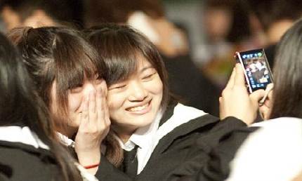 Two students in graduation attire smiling and posing for a photo