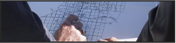 A close-up of hands pointing at a map with grid lines.