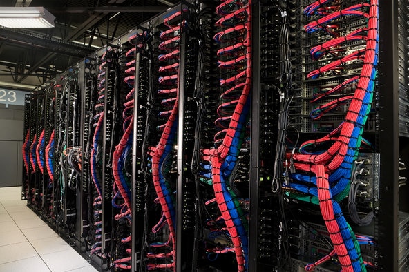 A row of server racks featuring organized cables in red and blue,showcasing the interior of a data center.