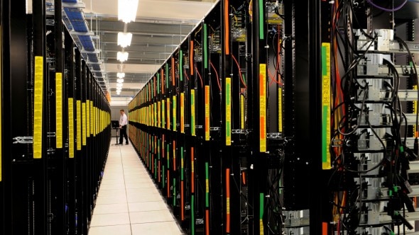 A view of a data center with rows of server racks,showcasing various colored cables and labeling.