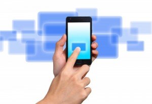 A hand holding a smartphone with a blue background,showcasing user interaction on the touch screen.