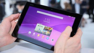 A person holding a tablet device with a purple interface display,showcasing various apps and widgets.