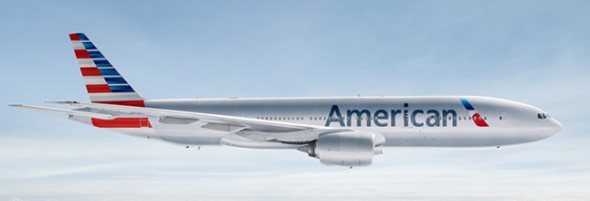 A side view of an American Airlines airplane in flight against a cloudy sky.