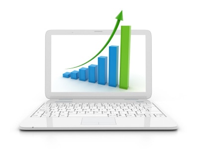 A white laptop with a graph displaying increasing bars and an upward arrow on its screen.