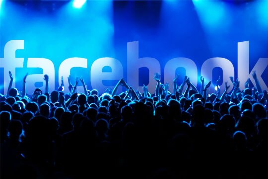 Silhouette of a crowd at a concert with the Facebook logo in the background,illuminated by blue lights.