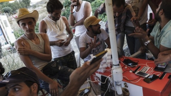 A group of men gathered around a table with mobile devices,engaging in conversation.