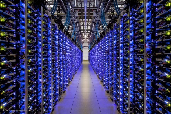 A view of a modern data center with rows of server racks illuminated by blue lights.