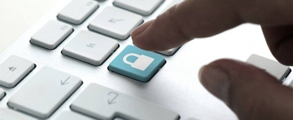 A close-up of a keyboard with a hand pressing a key that features a lock icon