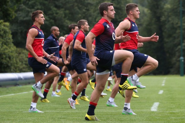 A group of rugby players participating in a practice session,performing warm-up exercises on a grassy field.