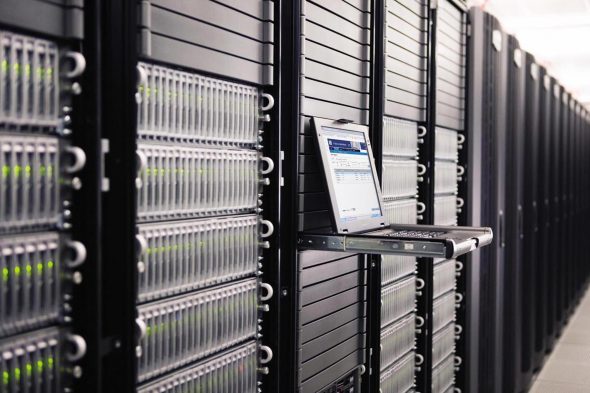 A row of server racks in a data center with a laptop positioned on a shelf.