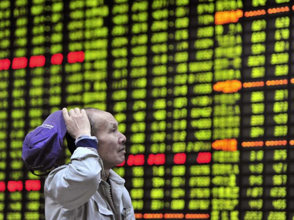 An individual observing a stock market display board filled with financial data.