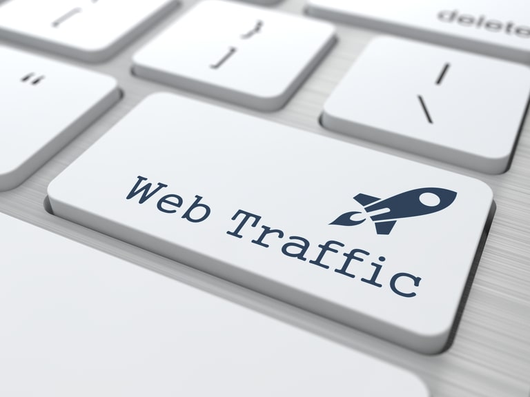 A close-up of a keyboard key labeled 'Web Traffic' with a rocket icon,representing digital marketing or website analytics.