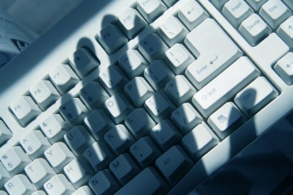 A close-up image of a computer keyboard casting shadows,highlighting the keys and the interplay of light.