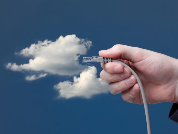 A hand holding an Ethernet cable,reaching towards fluffy clouds against a blue sky.