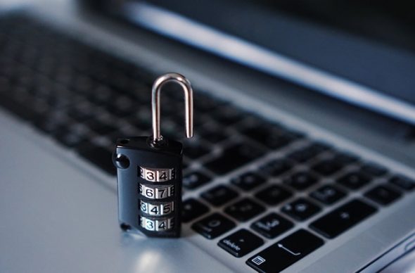 A close-up of a combination padlock resting on a laptop keyboard.