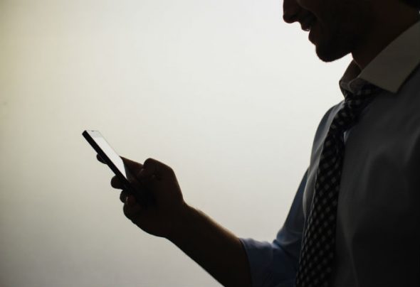 A silhouette of a man holding a smartphone,suggesting engagement with technology.