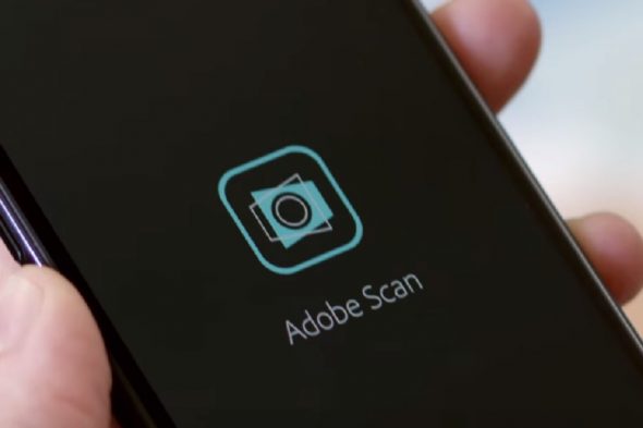 Close-up of a hand holding a smartphone displaying the Adobe Scan app icon.