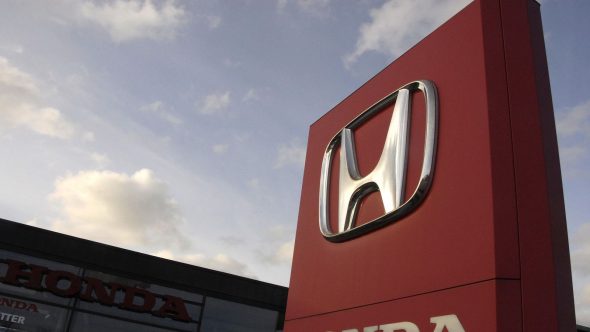 A close-up of a Honda dealership sign against a cloudy sky.