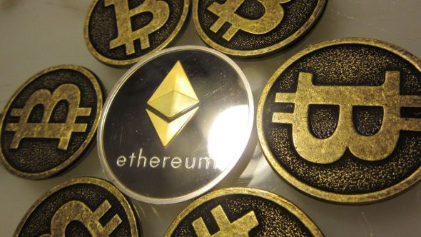 A collection of gold-colored cryptocurrency coins featuring the Bitcoin and Ethereum logos.