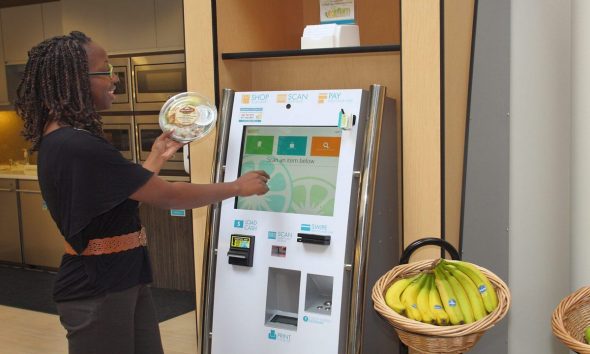 A person interacting with a digital vending machine while holding a plate