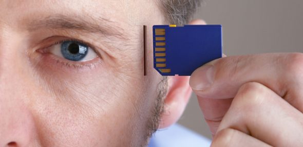 A close-up of a man holding an SD card next to his face