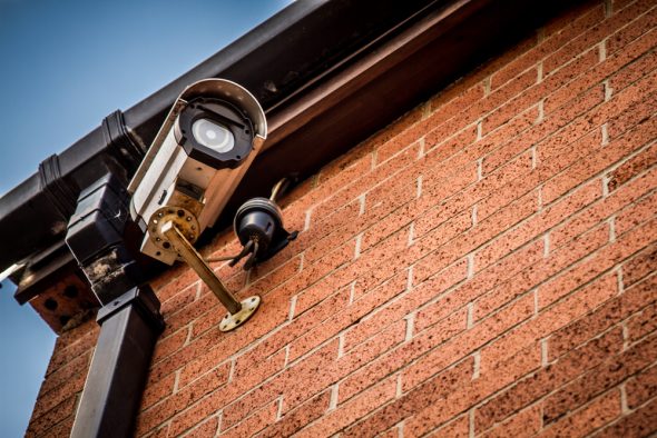 A close-up view of a security camera mounted on a brick wall along with a light fixture.