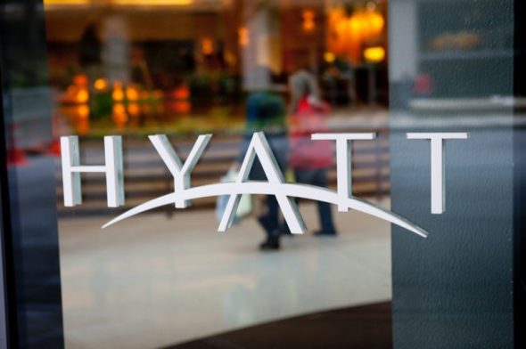 The reflective window displaying the Hyatt hotel logo with people in the background.