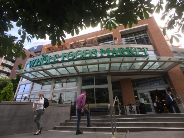 A view of the entrance to a Whole Foods Market with people walking in and out.