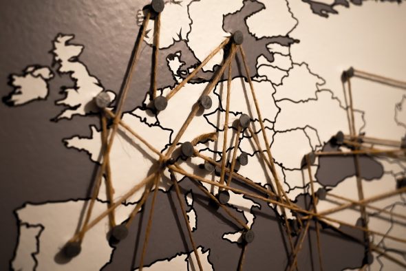 Close-up of a map of Europe with strings and pins creating connections.