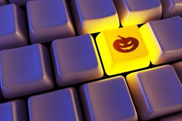 A close-up of a keyboard with one yellow key featuring a carved pumpkin design,illuminated among dark keys.