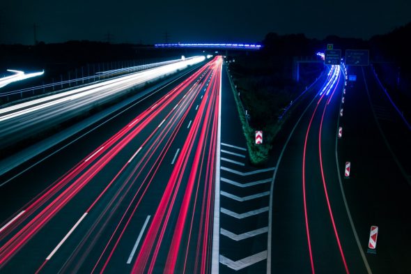 Long exposure of a highway at night showing light trails of vehicles.