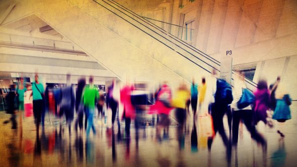 A blurred image of a busy airport terminal with people moving about and abstract colors.