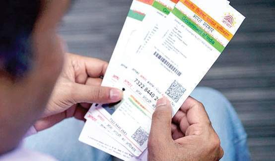 A person holding multiple Aadhaar cards,displaying personal and identification information.