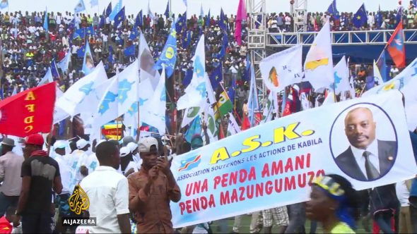 A large crowd at a political rally holding various flags and banners