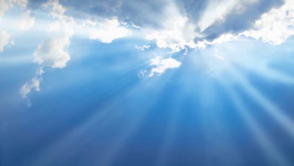 A serene sky with rays of sunlight breaking through fluffy clouds,illuminating the blue sky.