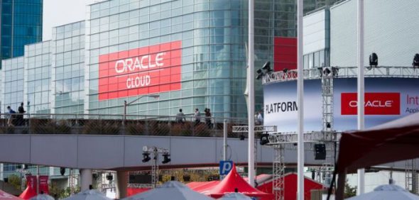 An exterior view of a conference venue featuring large signs for 'Oracle Cloud' and other Oracle branding.