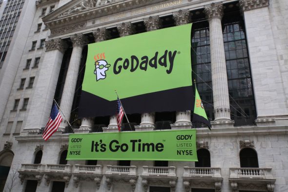 GoDaddy listing banner at the New York Stock Exchange with flags.