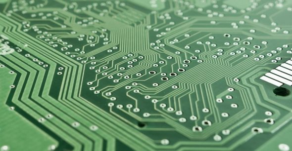 Close-up view of a green printed circuit board (PCB) showing intricate pathways and holes.