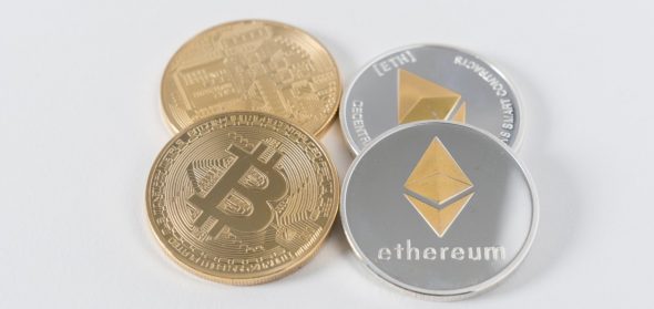 Two physical coins representing Bitcoin and Ethereum placed on a light background.