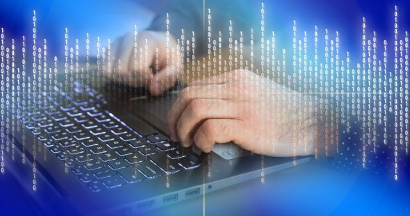 A close-up of hands typing on a laptop keyboard