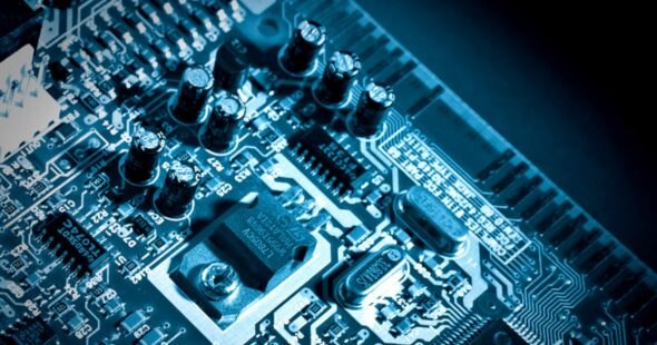 Close-up view of a blue circuit board with various electronic components and capacitors.