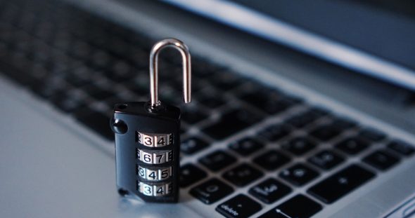 A black combination padlock placed on a laptop keyboard.