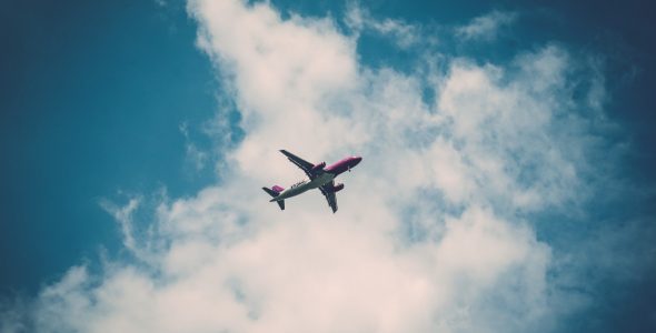 An airplane flying in a blue sky with white clouds.