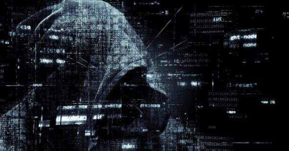 A silhouette of a hooded figure against a backdrop of digital code and data.