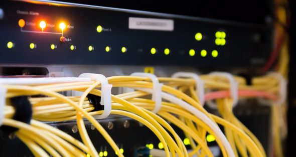 Close-up view of a network switch with illuminated indicators and organized yellow cables.