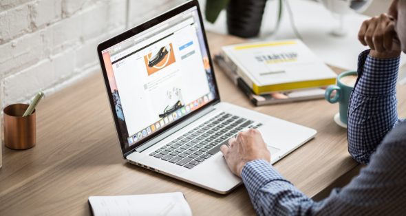 A person using a laptop on a wooden desk