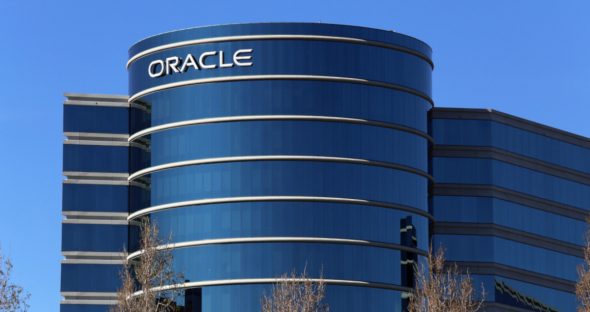 Exterior view of the Oracle building with a blue glass facade and the Oracle logo prominently displayed.