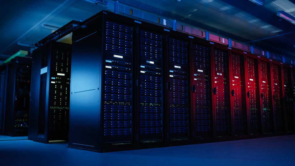 An interior view of a data center featuring rows of server racks illuminated with blue and red lighting.