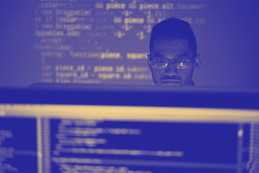 A person with glasses focused on coding