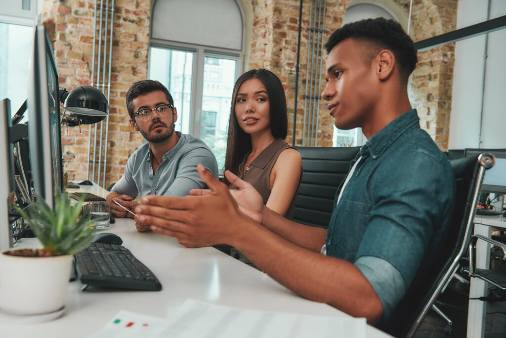 A group of three individuals engaged in a discussion at a modern office